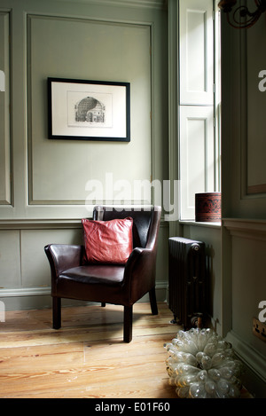 Premier étage salle de séjour, coin de détail. Chaise en cuir en coin par des murs lambrissés et des fenêtre à volets Banque D'Images