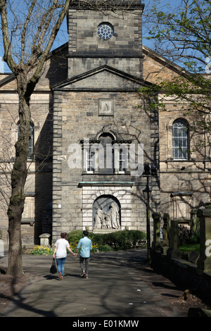 Un jeune couple holding hands en marchant par St Cuthbert's Churchyard. Banque D'Images