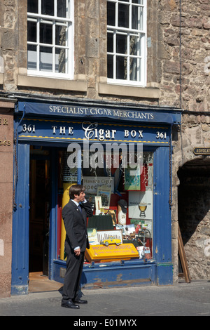 L'homme en costume sombre à parler sur son téléphone portable à l'extérieur de la boîte à cigares shop sur le Royal Mile, Édimbourg. Banque D'Images