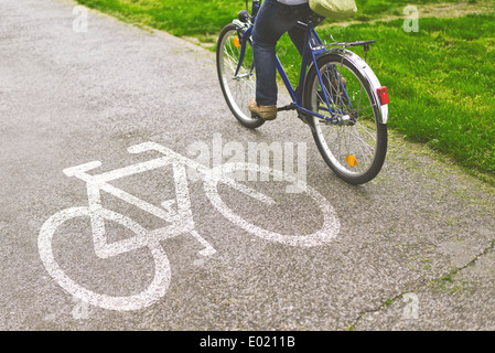 Pour se rendre à son travail à bicyclette. Woman riding bicycle sur une piste cyclable marquée avec symbole. Banque D'Images