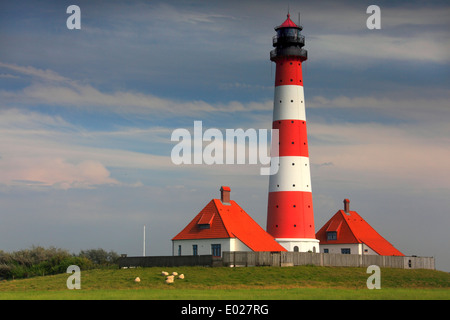 Photo de la rouge et blanc à rayures westerheversand, phare de la péninsule eiderstedt, avec Ciel et nuages de tempête, Allemagne Banque D'Images