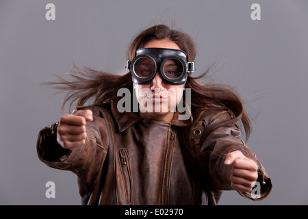 Funny Girl avec motorbiker grands verres et une veste en cuir faisant semblant de souffler Banque D'Images