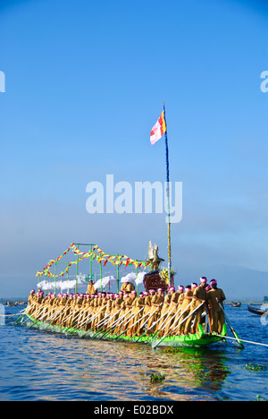 Leg-rameurs d'avancer en tirant sur la barge royale à travers le lac Inle pendant le festival Banque D'Images