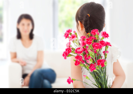 Petite fille à la mère et au masquage d'un bouquet d'œillets Banque D'Images