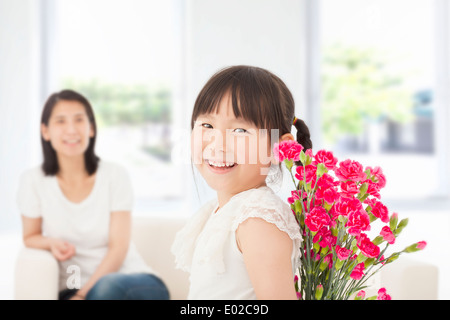 Petite fille à l'arrière et cache un bouquet d'œillets Banque D'Images