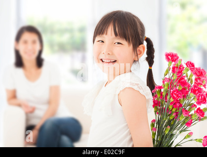 Jolie fille à l'arrière et cache un bouquet d'œillets Banque D'Images