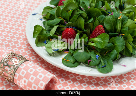 La mâche avec fraises et pétales de fleurs servi sur une assiette, serviette Banque D'Images