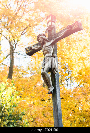 Jésus Christ sur la croix avec les arbres d'automne en arrière-plan. Cimetière à Stockholm, Suède. Banque D'Images
