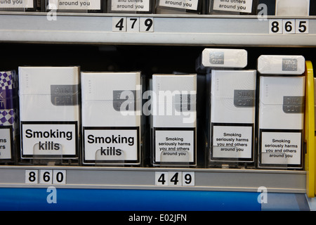Les marques de cigarettes dans un emballage avec des avertissements pour la santé au cabinet dans un petit magasin d'Irlande Banque D'Images
