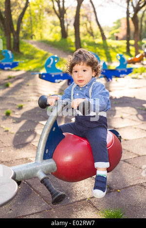 Petit garçon s'amusant sur une balançoire dans le parc de jeux pour enfants Banque D'Images