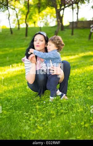 La maman et le petit garçon qui sort le pissenlit et de s'amuser à l'extérieur dans une journée ensoleillée Banque D'Images