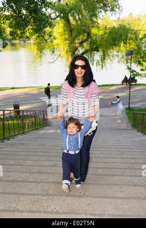 Mère d'aider son enfant à monter les escaliers dans la région de park Banque D'Images