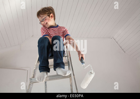 Un garçon assis sur un escabeau. Banque D'Images