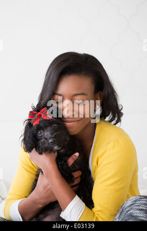 Une jeune fille de câliner son petit chien noir. Banque D'Images