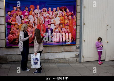 Femme plus âgée et plus jeunes filles en face de l'affiche de Mamma Mia comédie musicale dans le West End de Londres. Banque D'Images