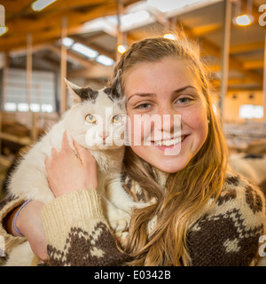 Adolescente avec une moustache de lait tenant son chat, exploitation agricole familiale, dans l'ouest de l'Islande Banque D'Images