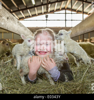 Jeune fille avec les agneaux nouveau-nés sur la ferme familiale, dans l'ouest de l'Islande Banque D'Images