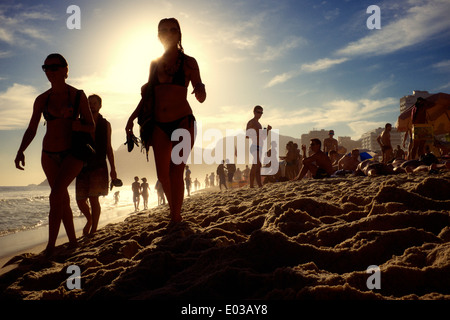 RIO DE JANEIRO, Brésil - le 21 février 2014 : Silhouettes d'hommes et de femmes marchant le long de la plage d'Ipanema au coucher du soleil. Banque D'Images