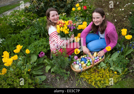 Chasse aux œufs de Pâques. Les filles avec leurs oeufs au chocolat et fleurs de printemps Banque D'Images