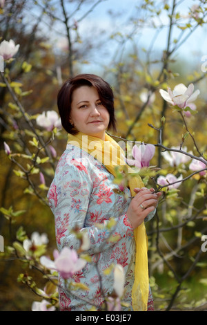 Jardin de printemps magnolia rose et une fille dans une écharpe jaune Banque D'Images