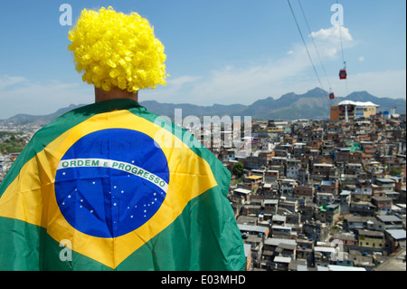 Fan de football brésilien au Brésil debout en face du pavillon de l'arrière-plan des bidonvilles favela à Rio de Janeiro Banque D'Images