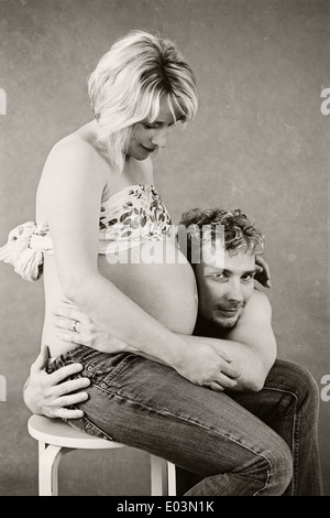 Un jeune père aimant pose sa tête sur le ventre de sa femme enceinte à écouter les battements de coeur de son bébé à naître Banque D'Images