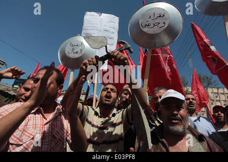 Gaza, la Palestine. 01 mai, 2014. Travaux palestinienne slogans chant comme d'autres l'attente lors d'un des bols mars pour la Journée internationale du travail dans la ville de Gaza, le Jeudi, Mai 1, 2014. L'arabe se lit, ''Le bol de la faim, la pauvreté et la famine, où est la conscience, '' Selon le Bureau des Nations Unies pour la coordination des affaires humanitaires, le taux de chômage dans la bande de Gaza est l'un des plus élevés au monde. Credit : ZUMA Press, Inc./Alamy Live News Banque D'Images