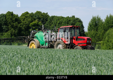 Les machines agricoles tracteur avec pulvérisateur long noir travaillant dans le secteur des Banque D'Images