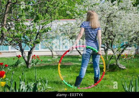 Woman hold hula hoop colorés sur fond nature vue arrière Banque D'Images