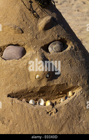 Vue rapprochée de la face faite de sable d'une plage avec des pierres et des cailloux pour les yeux et les coquillages pour les dents Banque D'Images