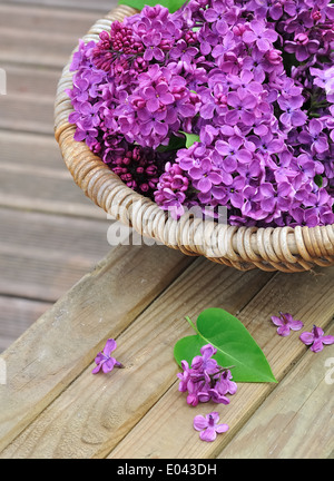 Fleurs lilas dans un panier placé sur une planche en bois Banque D'Images