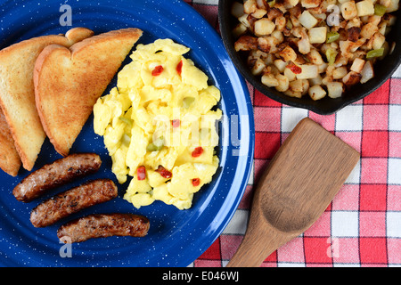 High angle shot of country style oeufs brouillés aux poivrons, des saucisses et des toasts. Le petit déjeuner est servi sur une table en bois rustique Banque D'Images