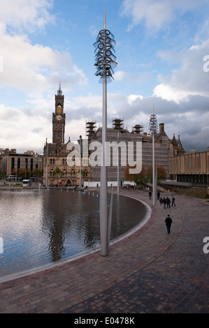 Sous le ciel bleu, les gens marchent à Bradford City Park au grand miroir courbe extérieure, l'hôtel de ville et sa tour impressionnante au-delà - West Yorkshire, Angleterre, Royaume-Uni. Banque D'Images