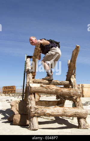 Man climbing over fence pour entrer dans une propriété privée Banque D'Images