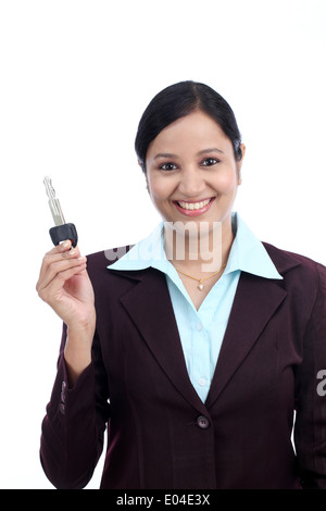 Happy young Indian business woman holding key against white background Banque D'Images