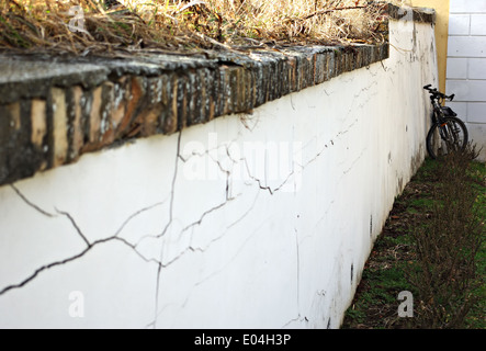 Location appuyé contre le vieux mur blanc craquelé. Banque D'Images