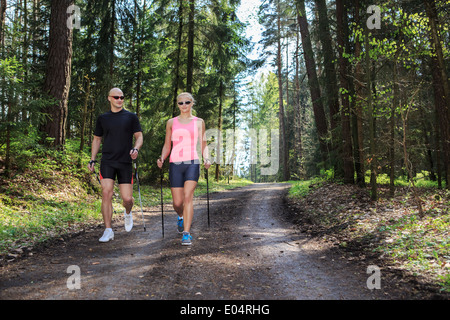 Un couple marche nordique à travers forêts Formation Banque D'Images
