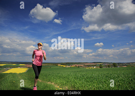 Woman jogging à travers champs au printemps Banque D'Images