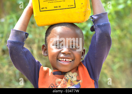 Un ugandese garçon transporte un bidon d'huile sur sa tête Banque D'Images