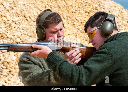 Jeune homme avec un pistolet à grenaille et sous un tir au pigeon d'argile sol coachés Banque D'Images