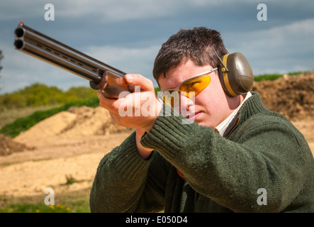 Jeune homme avec un pistolet à grenaille et sous un tir au pigeon d'argile sol Banque D'Images