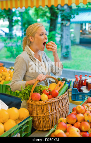 Une jeune femme achète des fruits et des légumes dans un marché hebdomadaire. Aliments frais et sains., eine junge Frau kauft Obst und Gemuese auf Banque D'Images