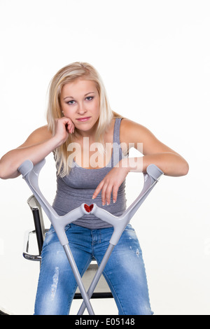 Une jeune femme avec des béquilles. Photo symbolique pour les accidents, les accidents et l'assurance budgétaire., eine junge Frau mit Kruecken. Sym Banque D'Images