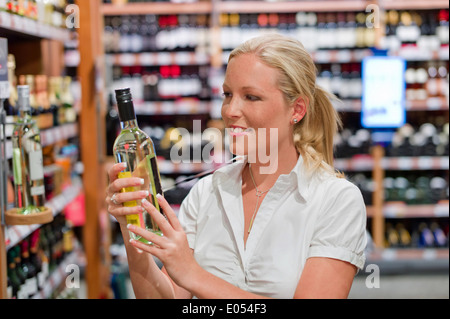 Une femme achète du vin dans un supermarché. Mettre du vin avec des vins du monde entier., Eine Frau kauft Wein in einem Dach Photovoltaik. Wein Banque D'Images