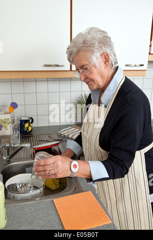 Un cadre supérieur par le lavage de la vaisselle, une Abwasch Geschirrs Seniorin beim votre Banque D'Images
