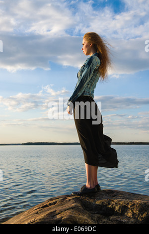 Belle jeune femme regarde l'horizon à terre - le vent souffle et ciel nuageux Banque D'Images