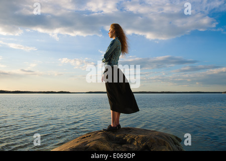 Belle jeune femme regarde l'horizon à terre - le vent souffle et ciel nuageux Banque D'Images