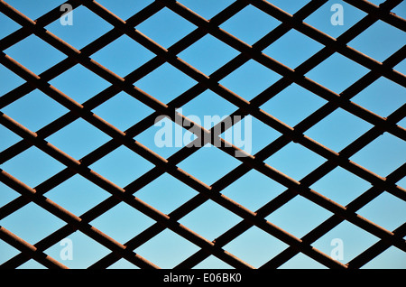 Chainlink Fence Against Blue Sky - Section d'une clôture de grillage simple torsion, derrière le ciel bleu comme un symbole de la captivité et de la liberté. Banque D'Images