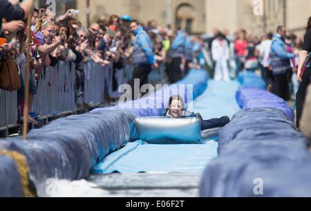 Bristol, Royaume-Uni. 04 mai, 2014. Les gens vers le bas de la vitesse d'un toboggan de 90m érigée sur la rue Park à Bristol. Luke Jerram artiste a organisé l'événement où 300 personnes va dévaler des feuilles de plastique trempé dans du liquide vaisselle et bordée de 400 balles de foin. 4 mai 2014 Crédit : Adam Gasson/Alamy Live News Banque D'Images