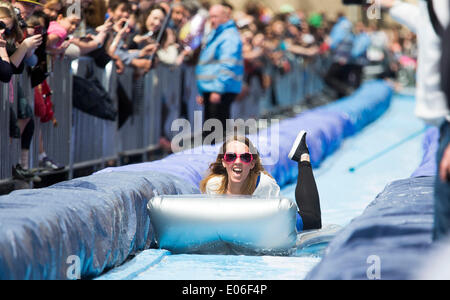 Bristol, Royaume-Uni. 04 mai, 2014. Les gens vers le bas de la vitesse d'un toboggan de 90m érigée sur la rue Park à Bristol. Luke Jerram artiste a organisé l'événement où 300 personnes va dévaler des feuilles de plastique trempé dans du liquide vaisselle et bordée de 400 balles de foin. 4 mai 2014 Crédit : Adam Gasson/Alamy Live News Banque D'Images